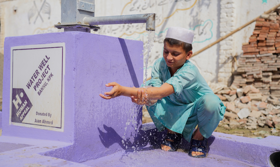 Young boy next to a water well