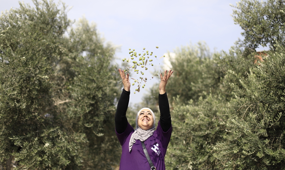 Human Appeal staff member throwing olives into the air