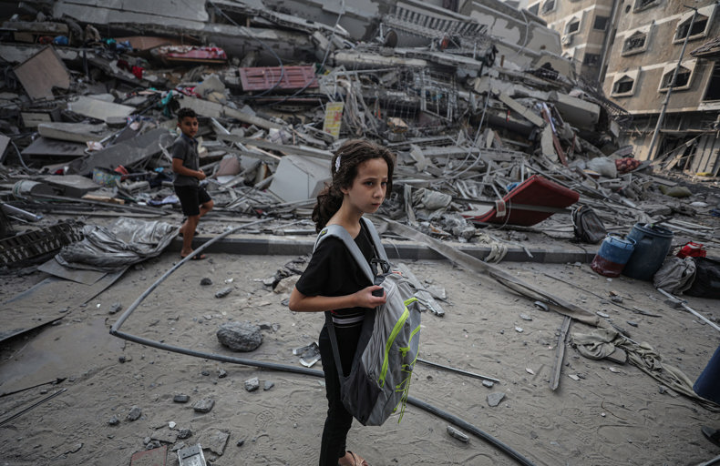 Child standing in front of a destroyed building in Gaza