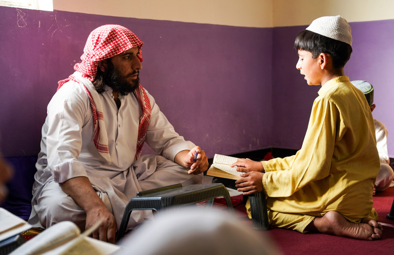 Man teaching child to read the Quran