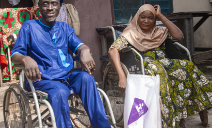 Two people in wheelchairs, a Qurbani bag between them