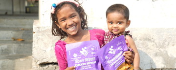 Two children, holding packets of chicken biryani