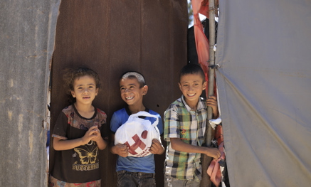Three children, one holding a Qurbani bag