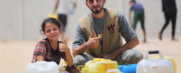 Staff member delivering water to children