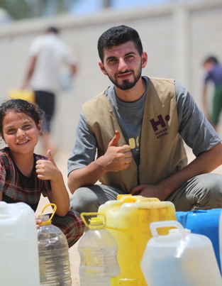 Staff member delivering water to children