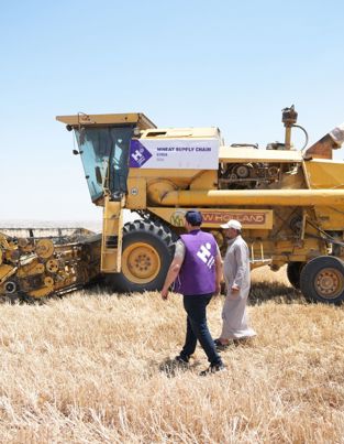 Human Appeal staff walking with a farmer, next to mechanical farming equipment