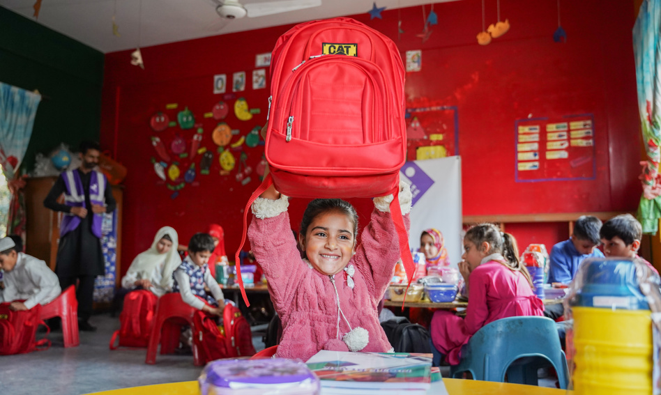 Young girl holding up a back to school kit in Pakistan