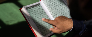 Person reading the Qur'an, tracing the line with their finger