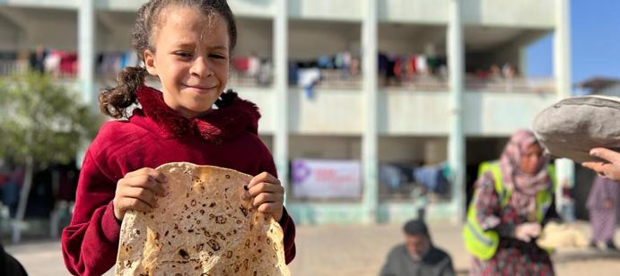 Youngster proudly displays freshly baked flatbread.
