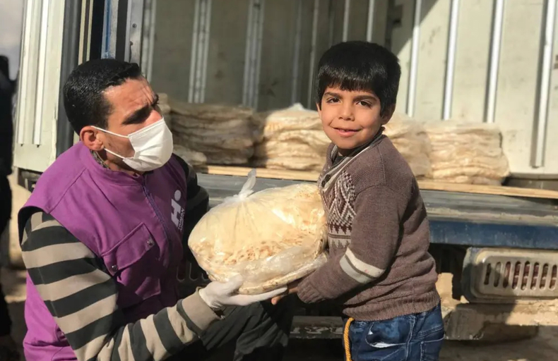 A child receiving daily bread bundles through our food security programme in Syria