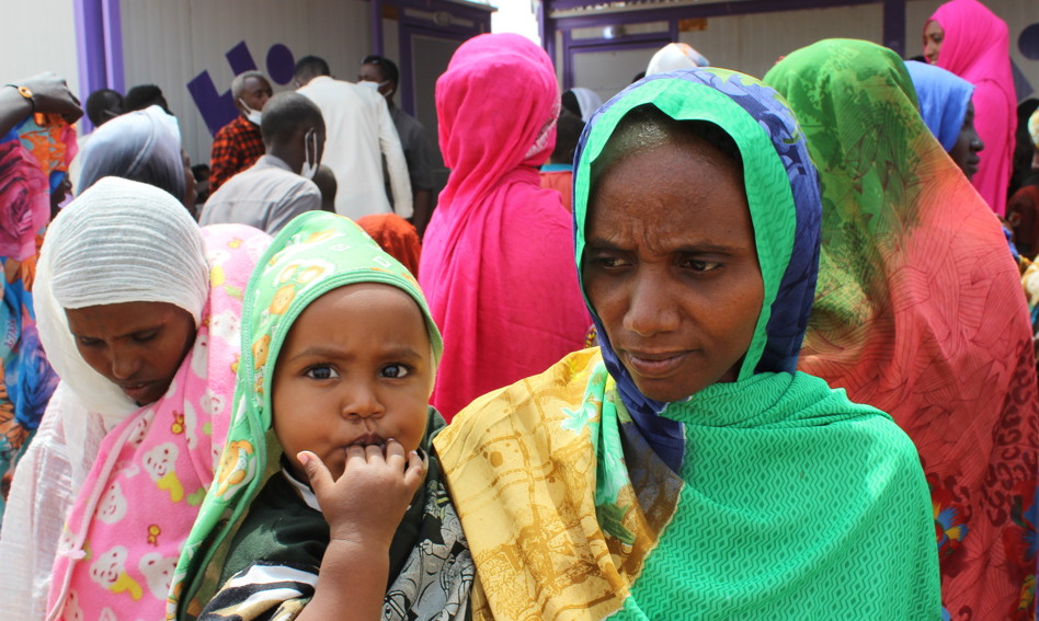 A crowd of women, the foremost one holding a child