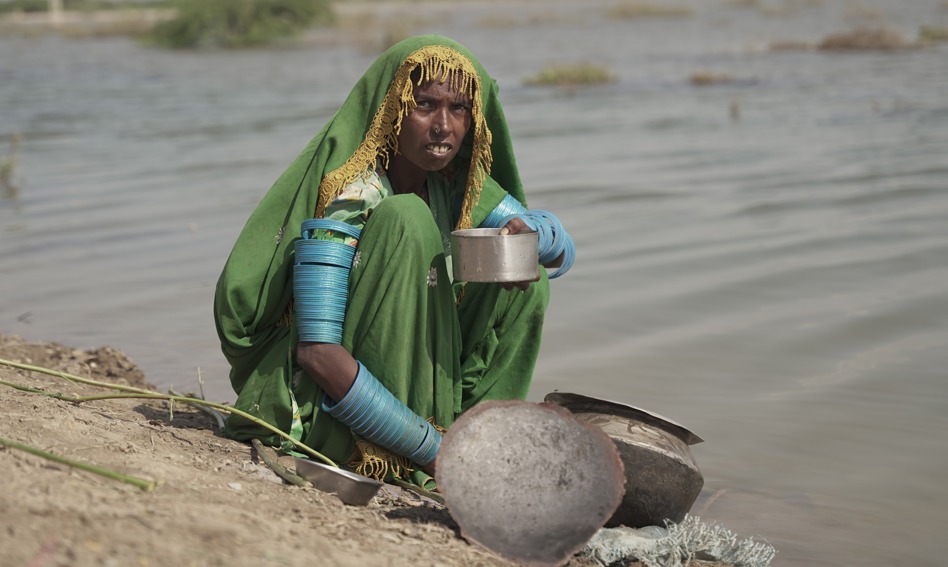 Woman sitting at the edge of a river with a bowl