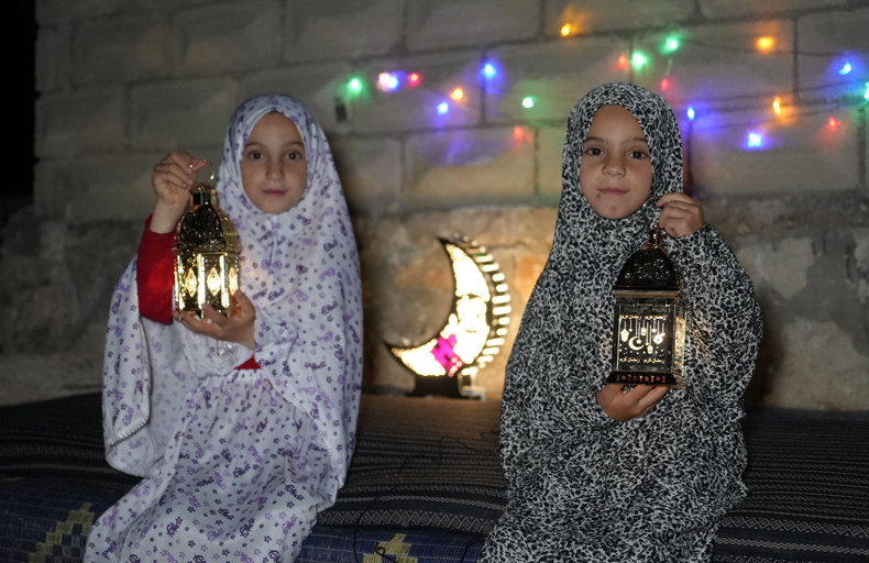 Two girls holding lanterns at night during Ramadan