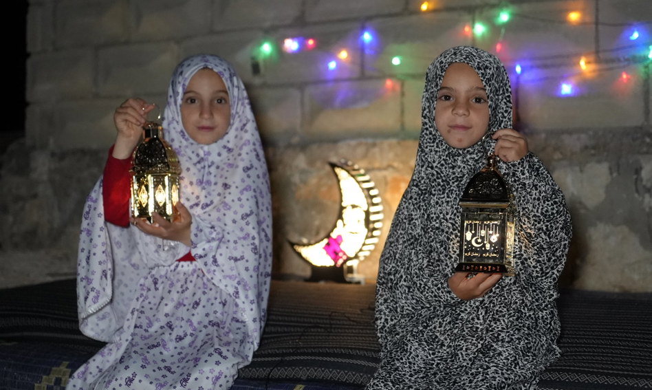 Two girls holding lanterns at night during Ramadan