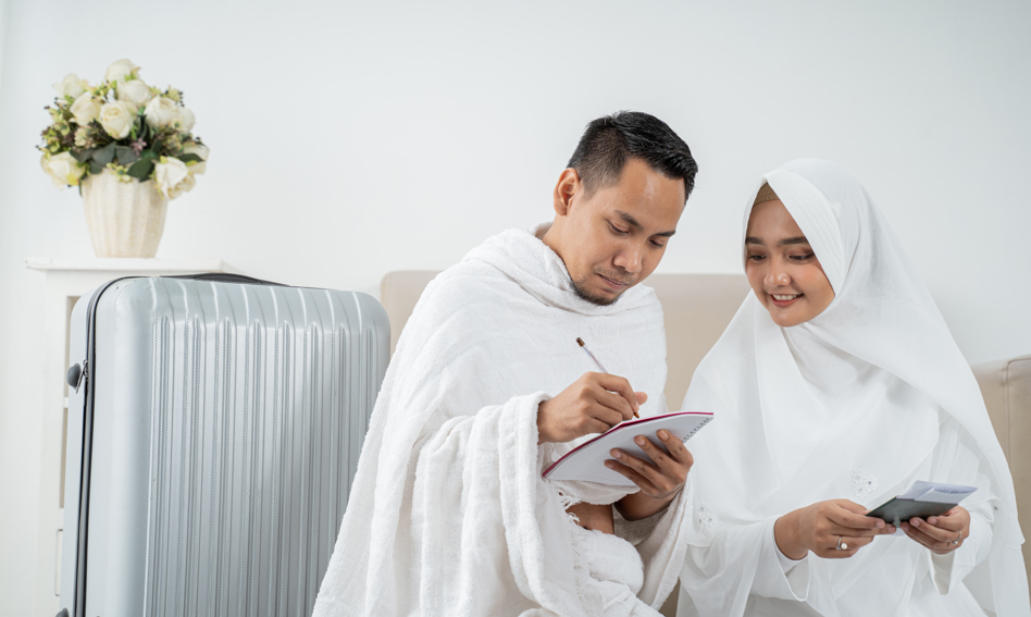 A man and a woman in pilgrim's garb with a suitcase, making a checlist