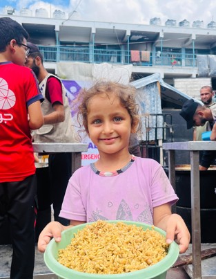 Child holding a hot meal in Gaza