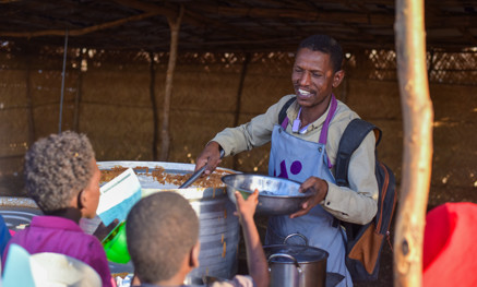 Man filling bowls with hot food
