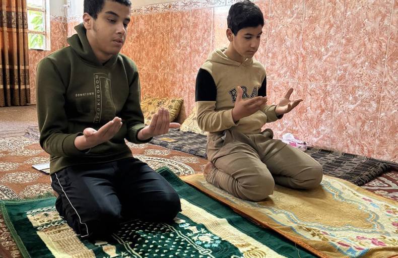 Two children offering Istikhara dua on prayer mats