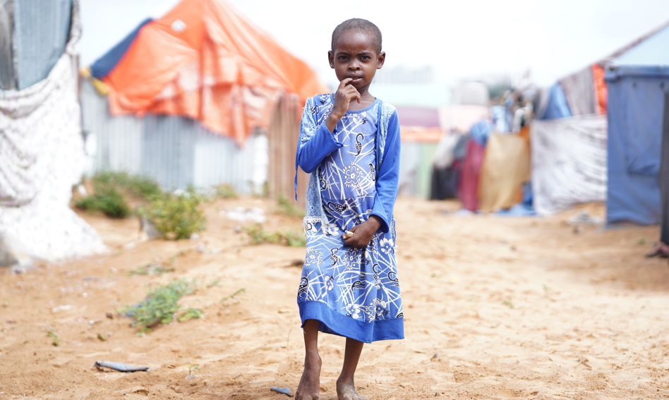 A young child surrounded by tents