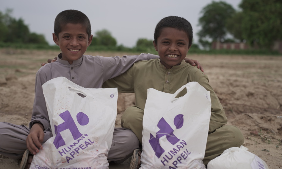 Two boys holding Qurbani bags